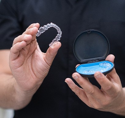 a dentist holding up an Invisalign tray