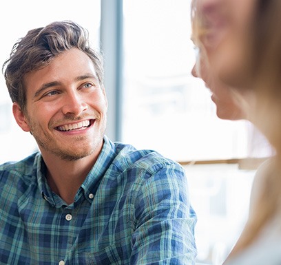 a smiling man talking to a friend