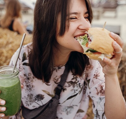 a woman eating a sandwich and drinking a smoothie