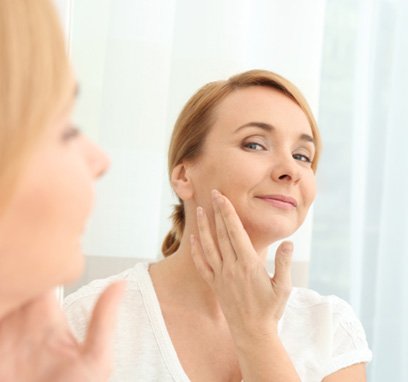 Woman examining her wrinkles in mirror