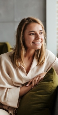 Smiling young woman in white blouse sitting on couch
