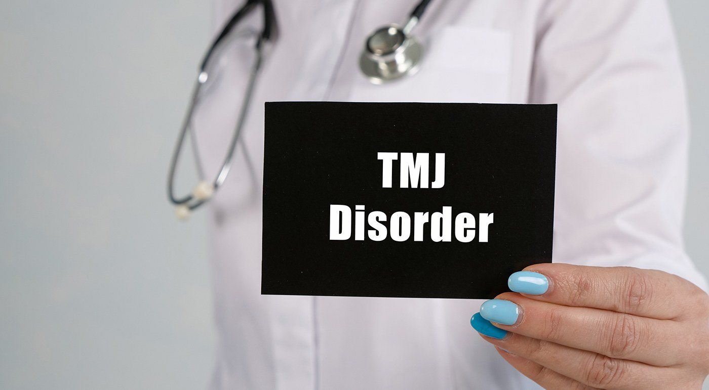 Doctor holding sign that says “TMJ disorder”